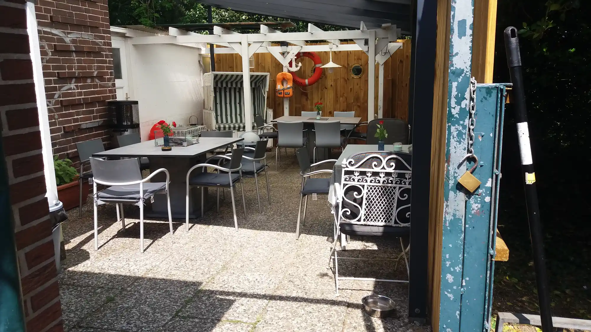 Gemütlicher Kaffeegarten von Bei Andy in Lübeck mit Sitzplätzen, weißer Pergola, Grillbereich und rustikalem Flair – der beliebte Kiez-Treffpunkt im Falkenviertel